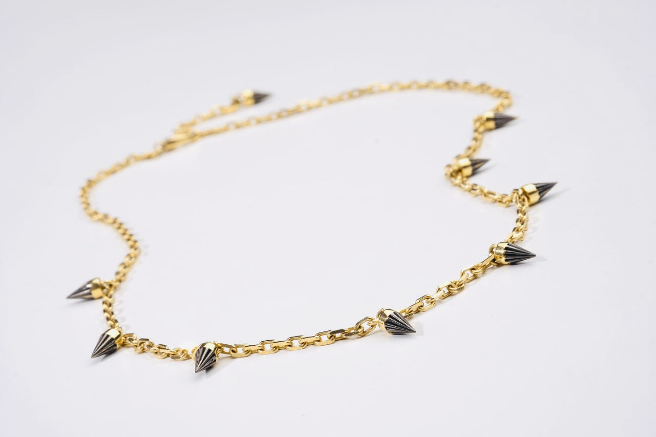 Woman with solid yellow gold necklace with multiple pendants.