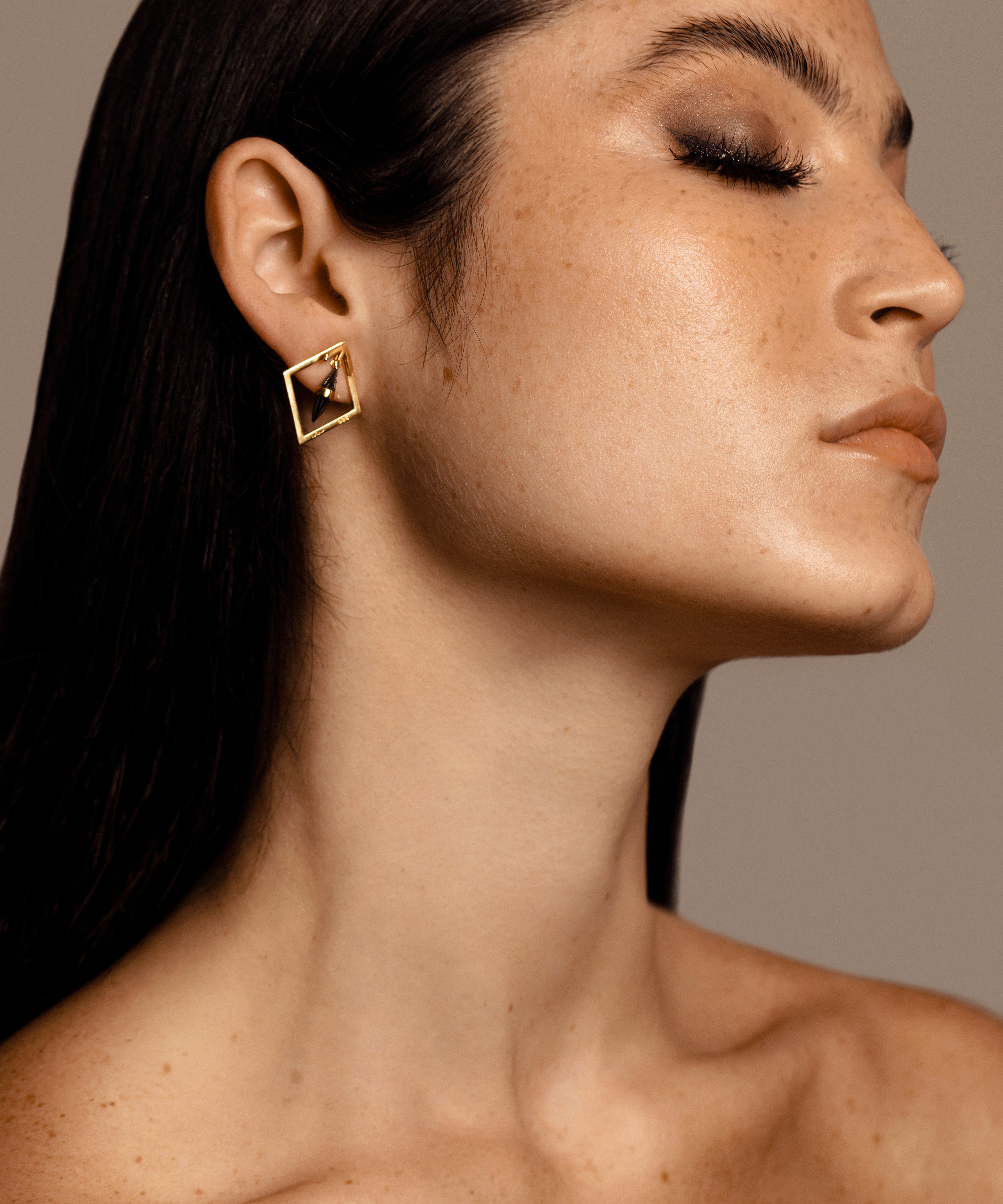 Woman with solid yellow gold diamond shaped earrings with black centre