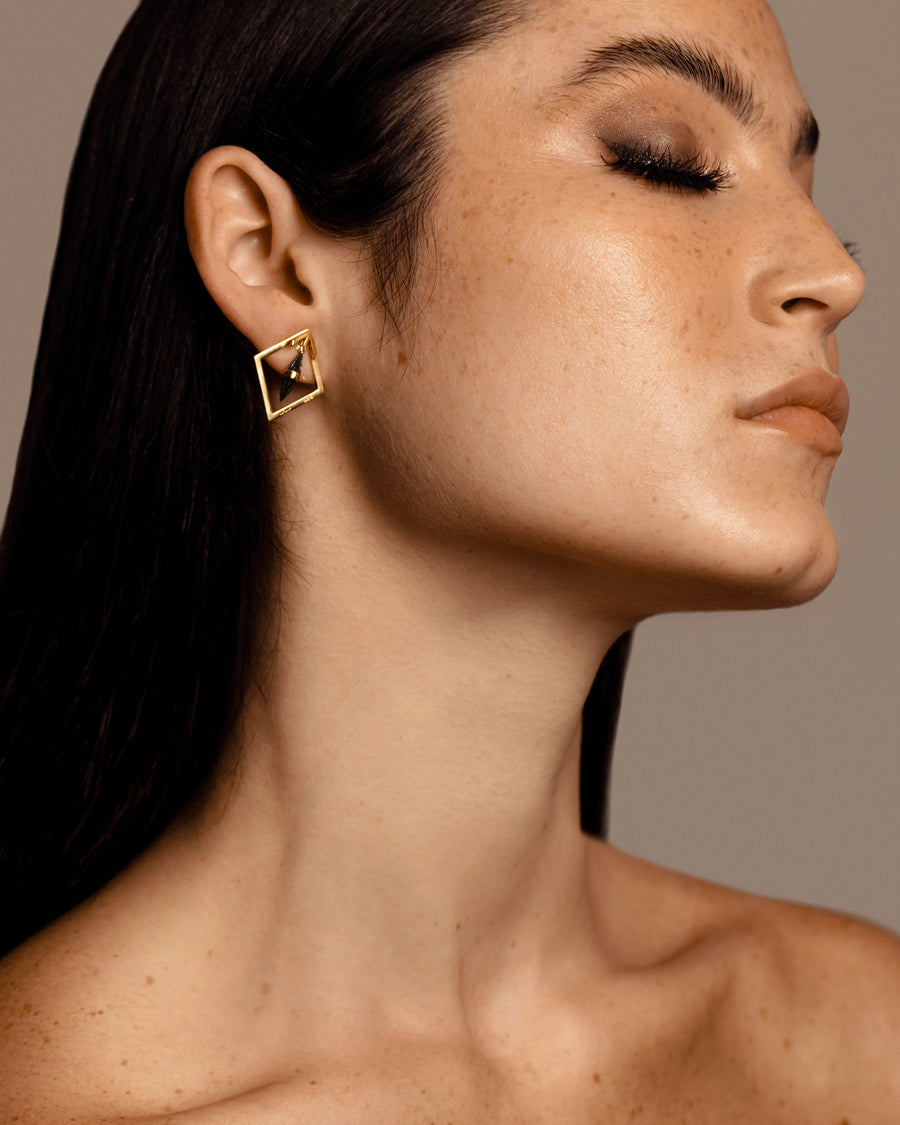 Woman with solid yellow gold diamond shaped earrings with black centre